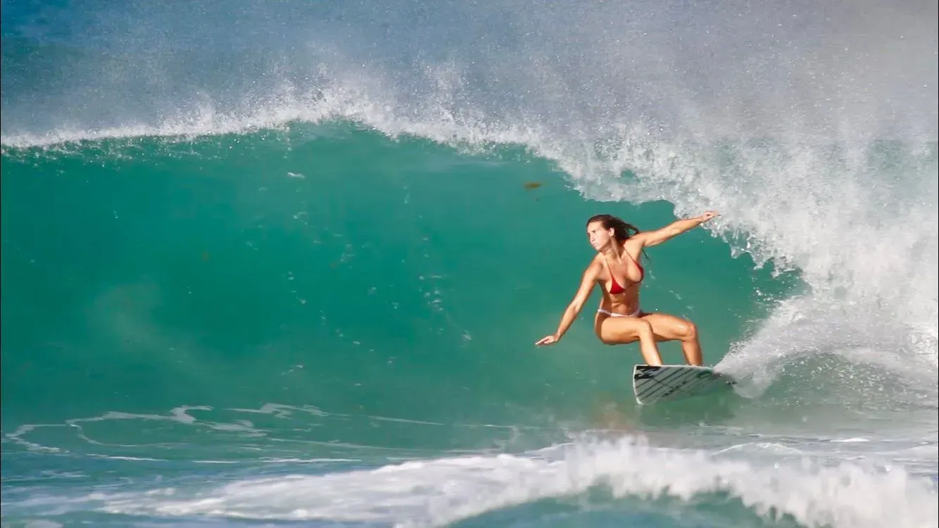A woman surfing perfect waves in the warm waters of Barbados