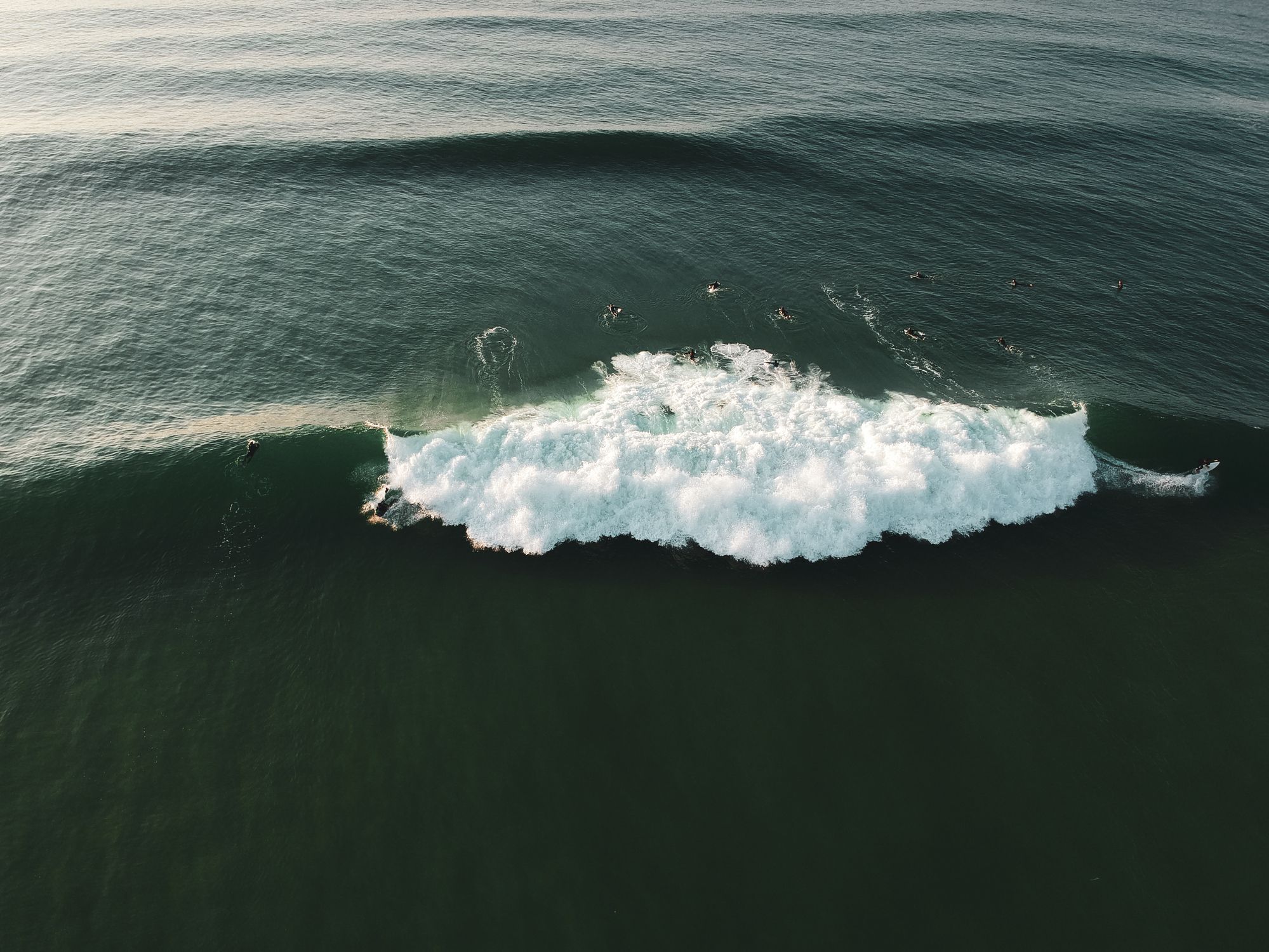 An aerial view of two surfers riding a perfect A-frame wave in Ericeira, Portugal