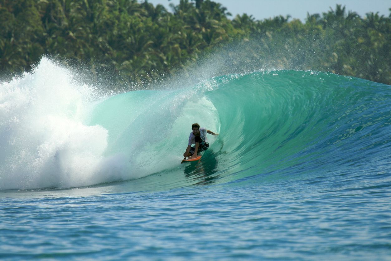 surfer getting tubed at Greenbush in Mentawai Islands, one of the best surf destinations in August